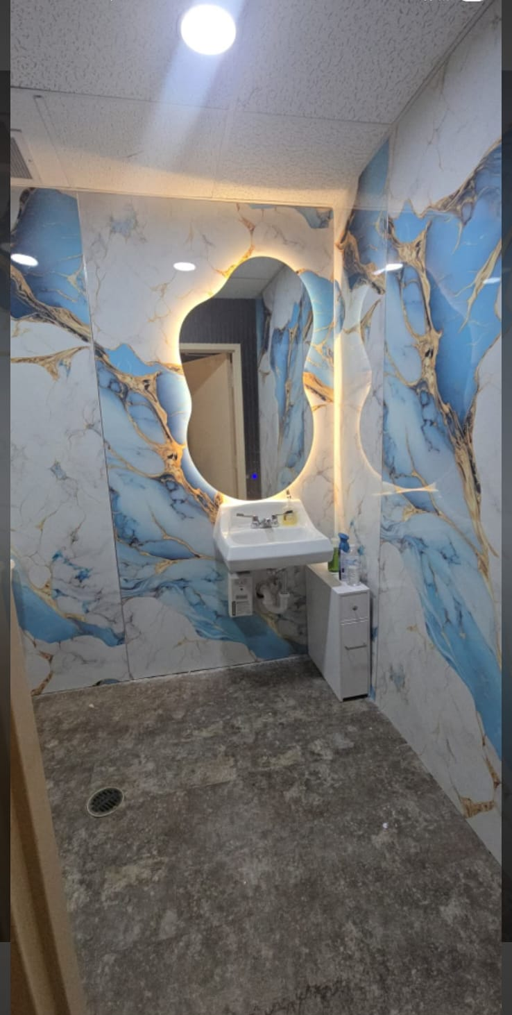 Baño revestido en mármol PVC azul y dorado con espejo retroiluminado