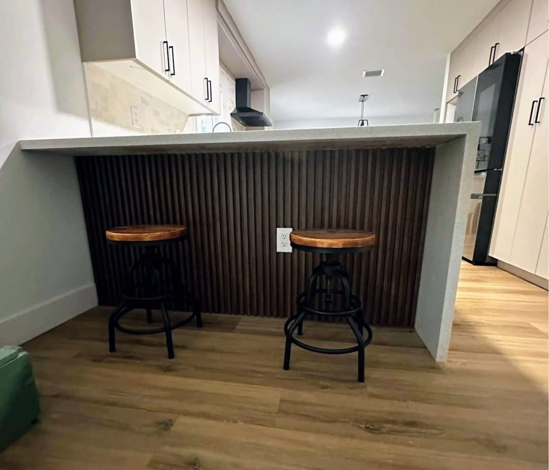 Barra de cocina con panel de lamas de madera, cubierta de mármol PVC y taburetes altos