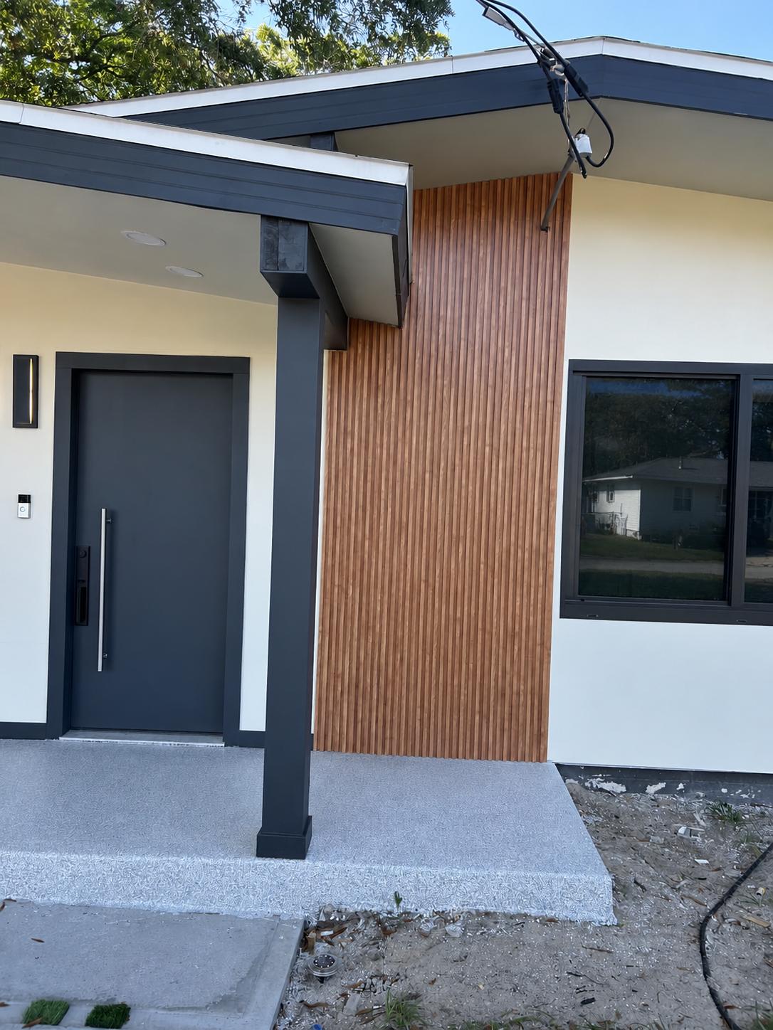 Fachada de entrada con panel de lamas de madera WPC junto a la puerta