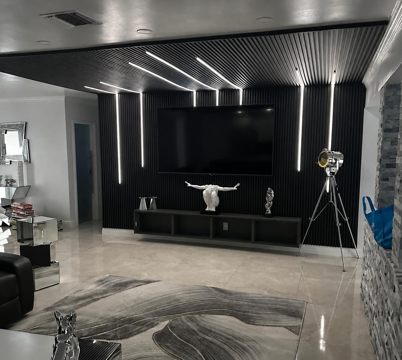 Sala con panel decorativo de lamas negras, techo iluminado y TV
