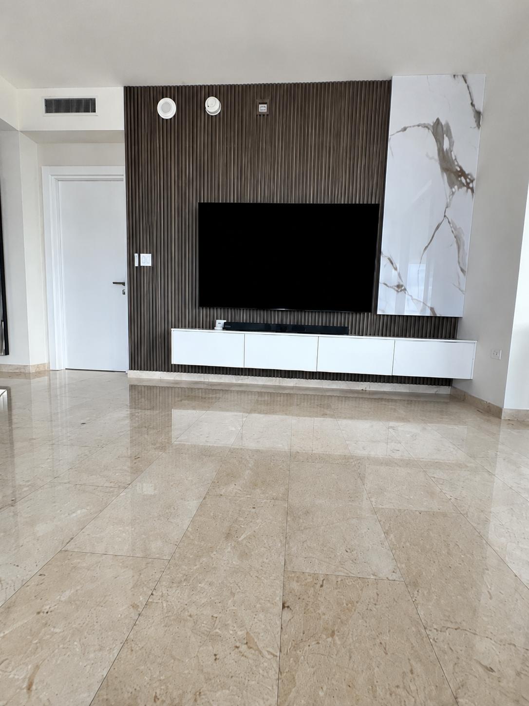 Panel de televisor con lamas de madera, mármol PVC y consola blanca flotante